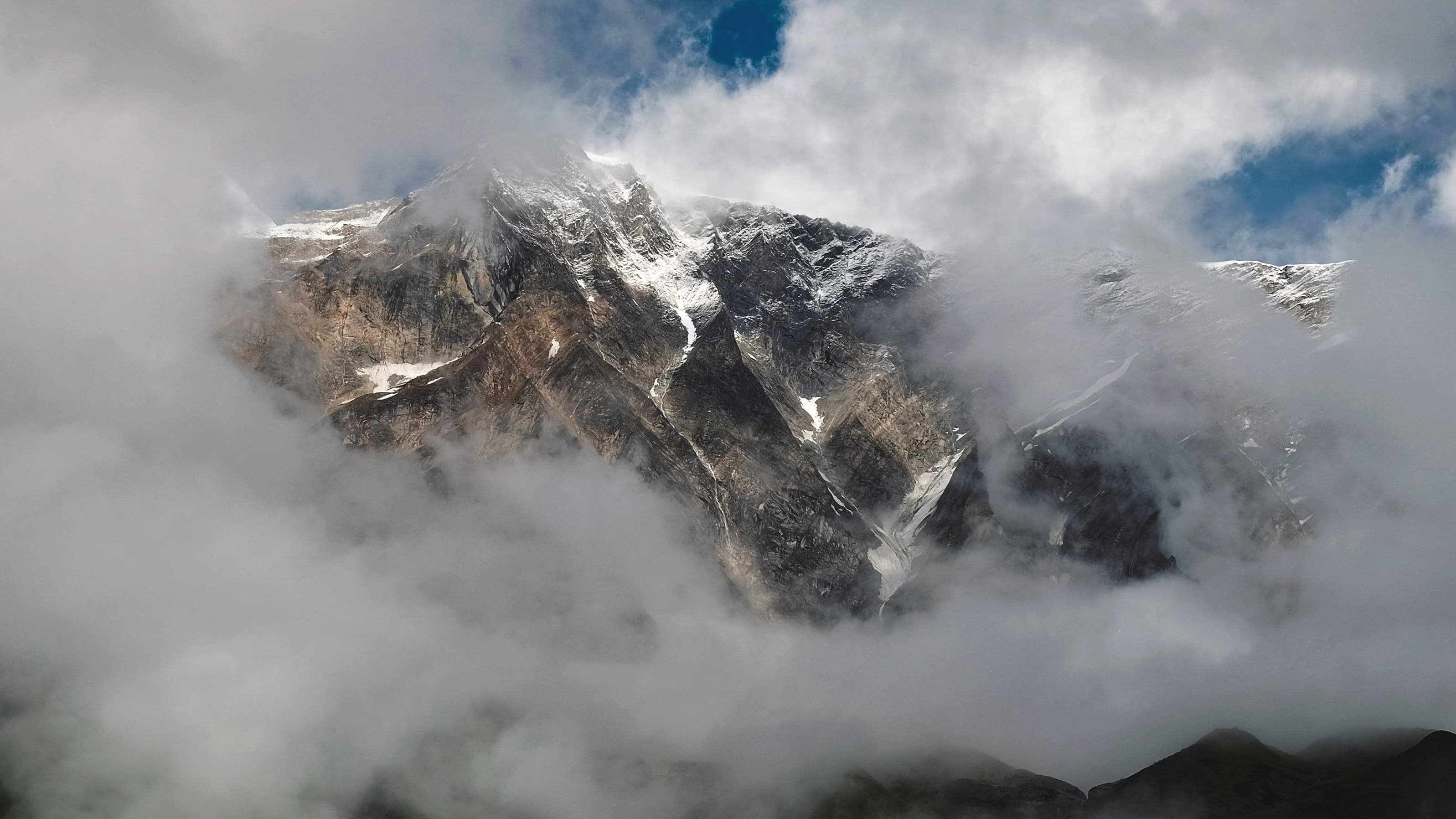 Rock face of a Himalayan peak emerging through swirling cloud