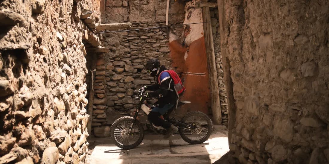E-cyclist riding through a narrow stone alley in a Mustang village